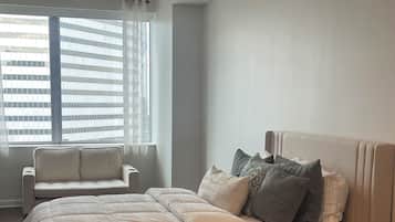 A bedroom with a bed, a nightstand, a chair, and a ceiling fan.