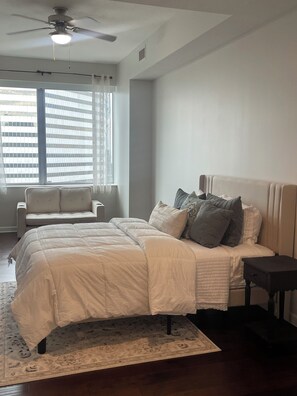 Une chambre à coucher avec un lit, une table de chevet, une chaise et un ventilateur de plafond.