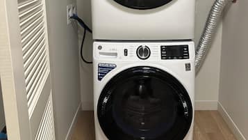 A stacked washer and dryer unit in a laundry room with a vent hose.