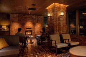 A cozy lounge area with a brick fireplace, comfortable seating, and a patterned floor. - UNWIND HOTEL & BAR OKUNIKKO (Nikko)