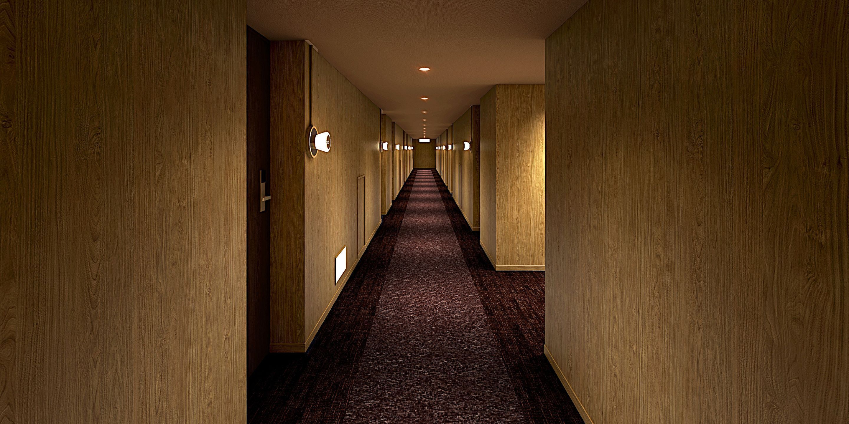 A long, narrow hallway with wooden walls and carpeted floors, illuminated by wall-mounted lights.