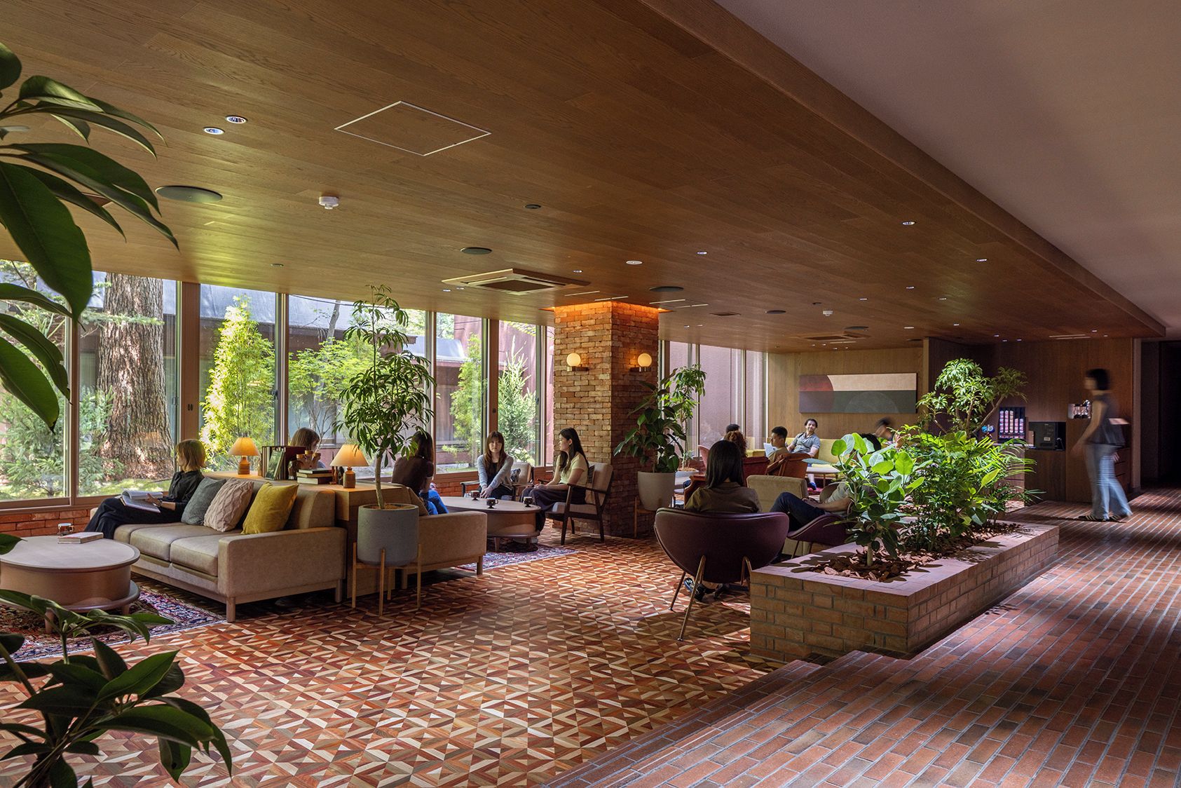Un espace intérieur vaste et lumineux, aménagé avec des sièges, de grandes fenêtres et des plantes d’intérieur.