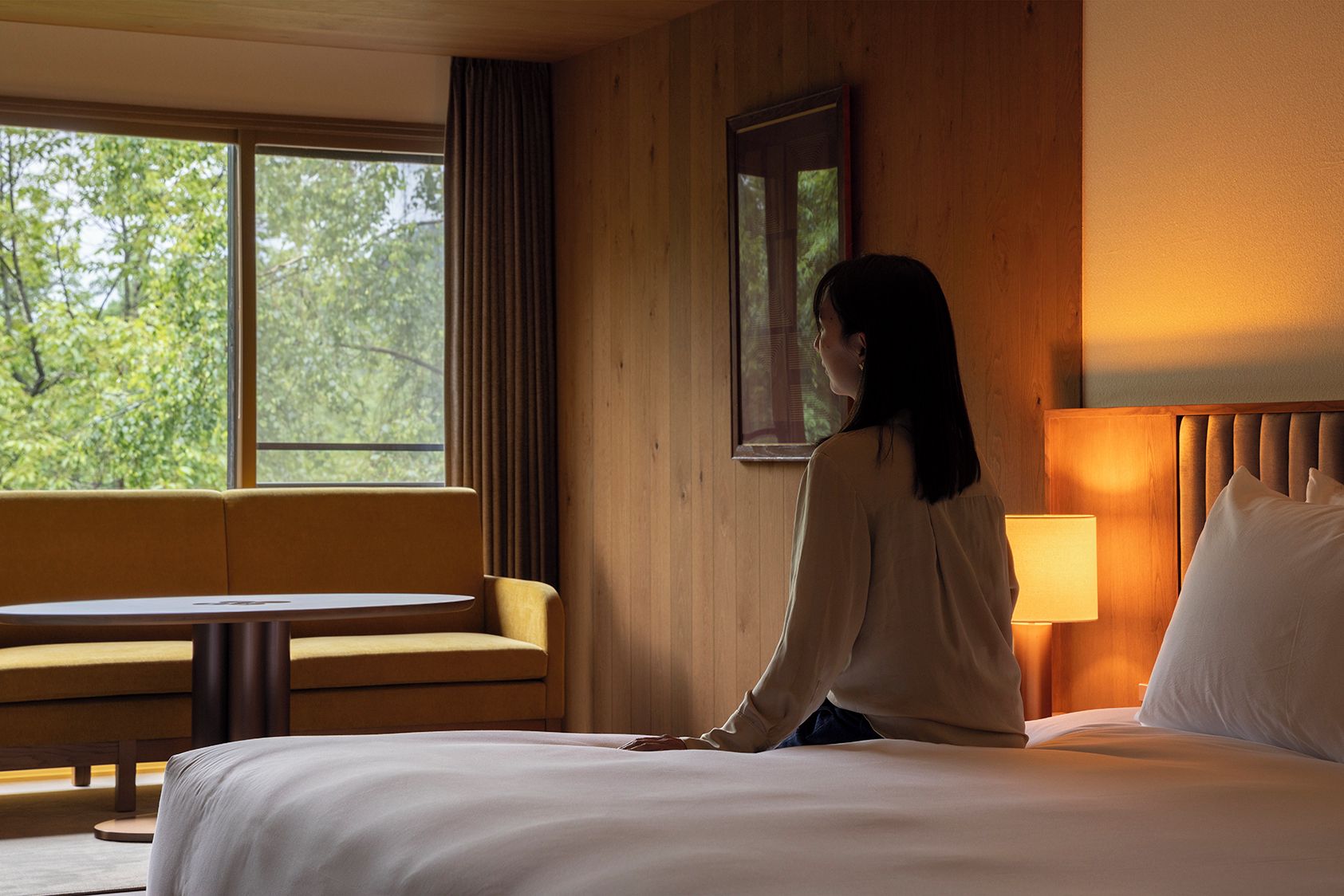 A hotel room with a bed, a sofa, a table, and a window with curtains.