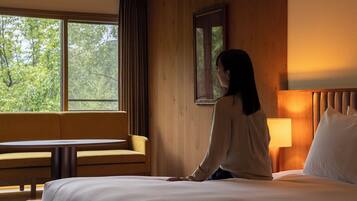 A hotel room with a bed, a sofa, a table, and a window with curtains.