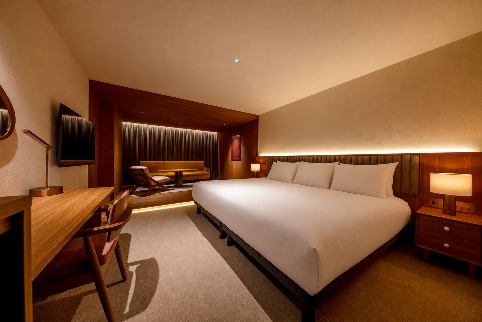 A hotel room with a large bed, a desk, a chair, a television, and a window with curtains.