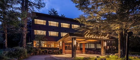 A multi-story hotel with a well-lit entrance and a neon sign.