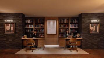 A library with two desks, bookshelves, and framed artwork on the walls.