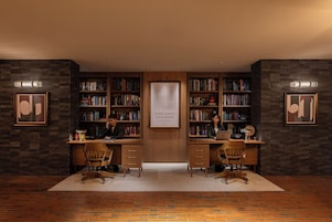 Une bibliothèque avec deux bureaux, des étagères et des œuvres d’art encadrées accrochées aux murs.