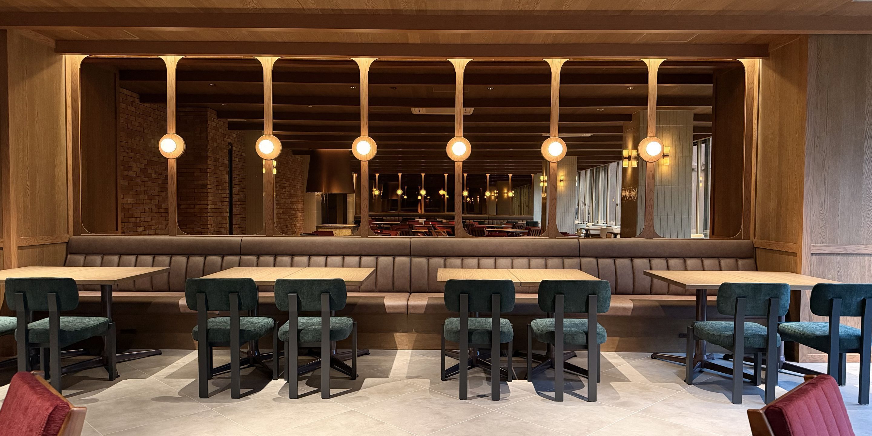 A restaurant interior with booths, high-top tables, and hanging pendant lights.
