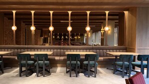 A restaurant interior with booths, high-top tables, and hanging pendant lights.
