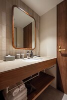 A modern bathroom with a wooden vanity, a large mirror, and a built-in towel rack.