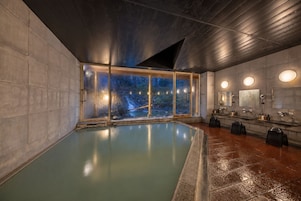 A modern indoor swimming pool with a view of a rocky landscape through large windows.