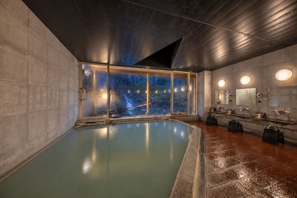 Una piscina interior moderna con vistas a un paisaje rocoso a través de amplios ventanales.