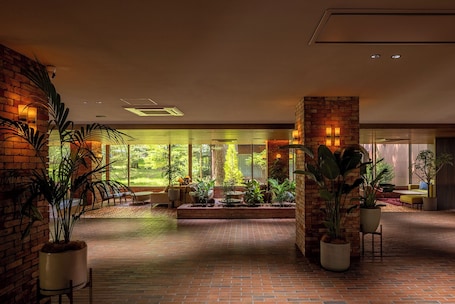 A spacious indoor area with brick walls, large windows, and potted plants.