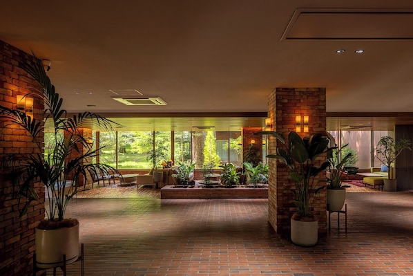 A spacious indoor area with brick walls, large windows, and potted plants. - UNWIND HOTEL & BAR OKUNIKKO (Nikko)