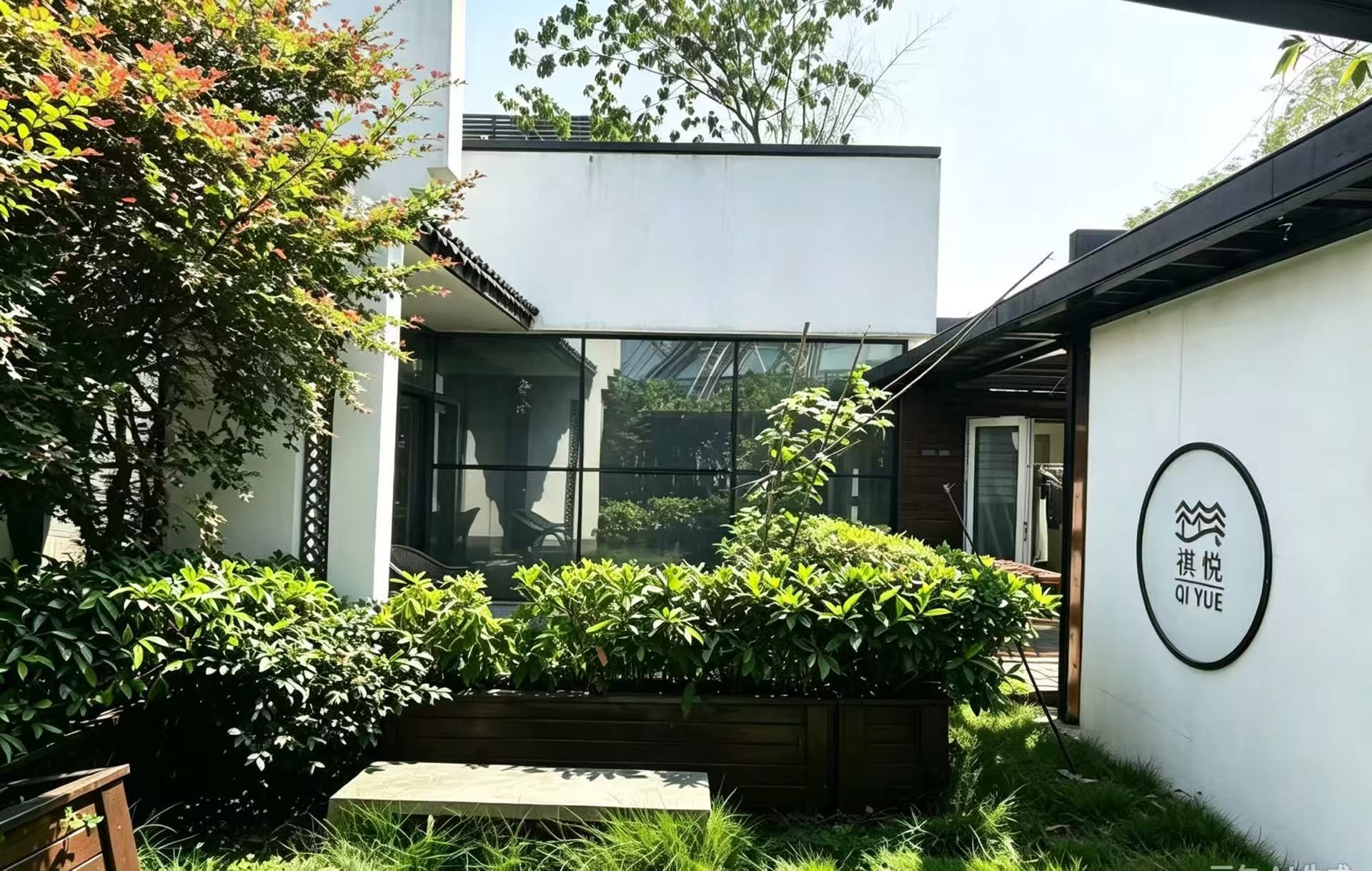 A modern building with a glass facade, a wooden deck, and a sign with Chinese characters.