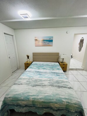 Ein Schlafzimmer mit Bett, Nachttisch, Wandbild und einer Tür.