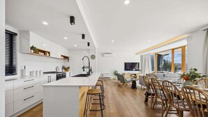 A modern kitchen with white cabinetry, a central island, and bar stools. - The Lakehouse Jindabyne (Jindabyne)