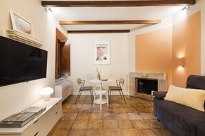 Ein Wohnzimmer mit Flachbildfernseher, Kamin, Esstisch mit Stühlen und einer Couch.