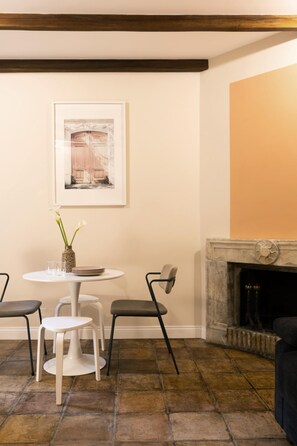 A room with a fireplace, a round table with chairs, and a framed picture on the wall. - The Secret Terrace in Navona (ROMA)