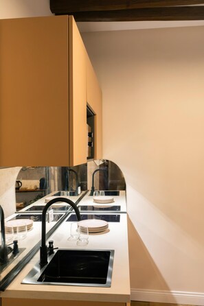 A kitchen with a sink, faucet, and a countertop with plates and glasses. - The Secret Terrace in Navona (ROMA)