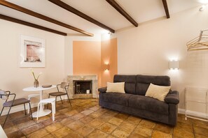 A living room with a fireplace, a sofa, a table with chairs, and a hanging light fixture. - The Secret Terrace in Navona (ROMA)