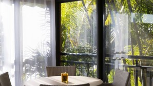 Ein Essbereich mit Tisch und Stühlen, große Fenster mit Blick auf dichtes Grün.