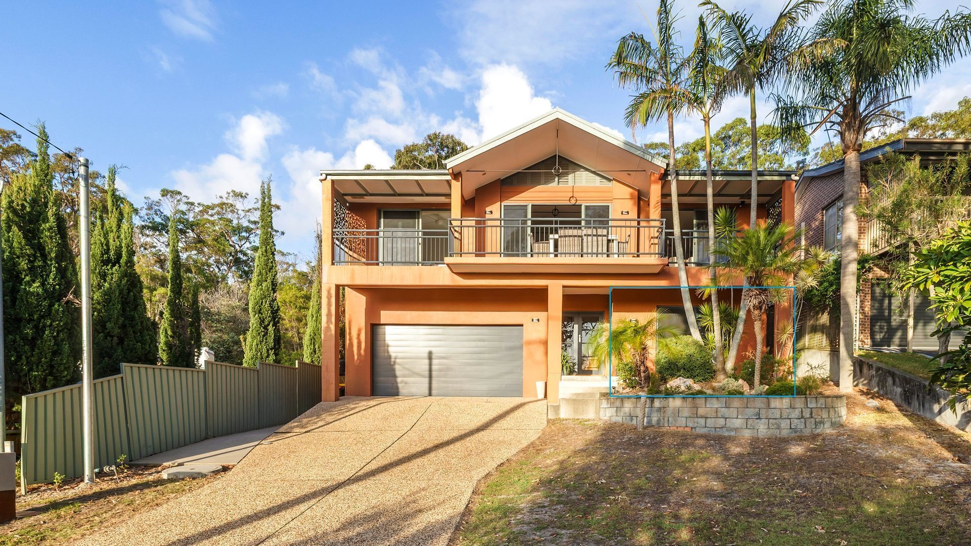 A two-story house with a garage, a balcony, and a well-maintained garden.