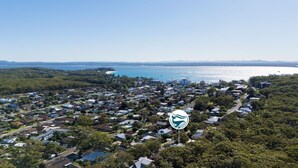 An aerial view of a coastal town with residential houses, a beach, and a large body of water. - Studio Retreat on  Flannel Flower Shoal Bay (Shoal Bay)