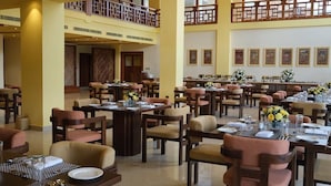 A spacious dining area with multiple tables and chairs, a second-floor balcony, and framed artwork on the walls. - Terma Linca Paro (Paro)
