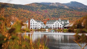 A lakeside hotel with a large building, a dock, and a mountain backdrop. - Wanderlust - New 2026 Ski Townhome - Walk to Town Square - Game Loft & Bar (Waterville Valley)