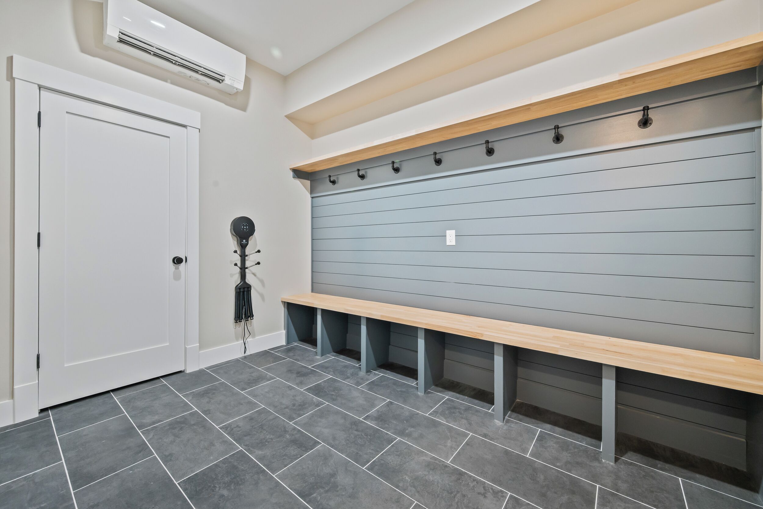 A hallway with a bench, a door, and a wall-mounted rack.