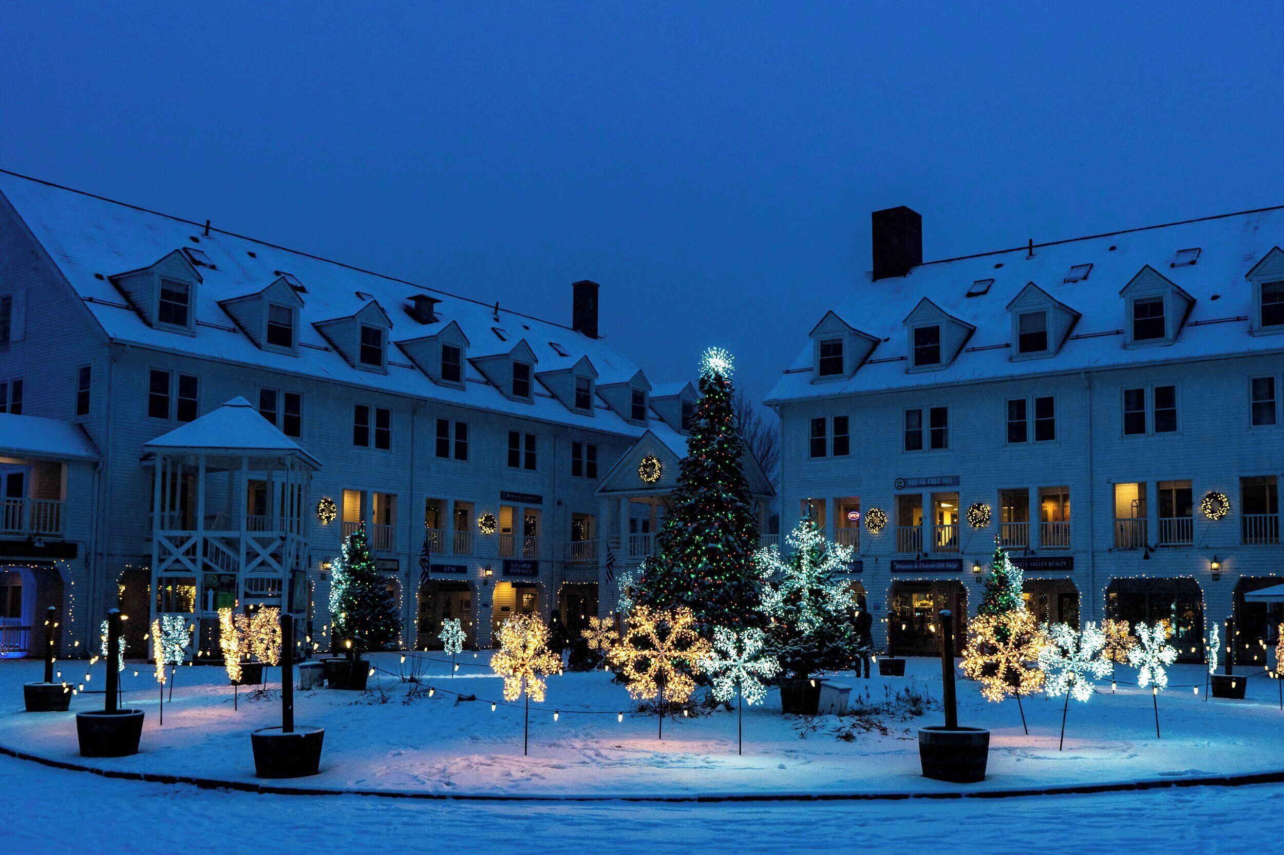 A hotel with multiple stories, snow-covered roofs, and a Christmas tree with lights.