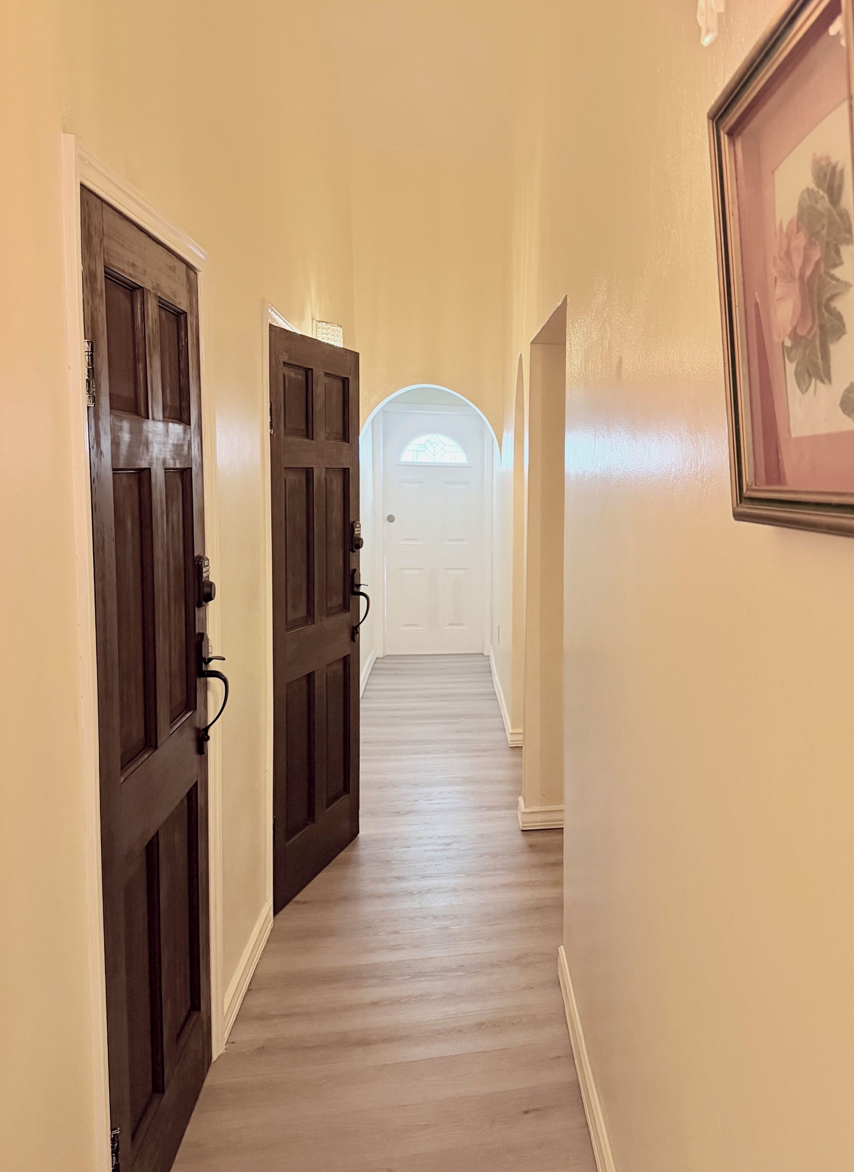 A hallway with wooden doors and a white door at the end.