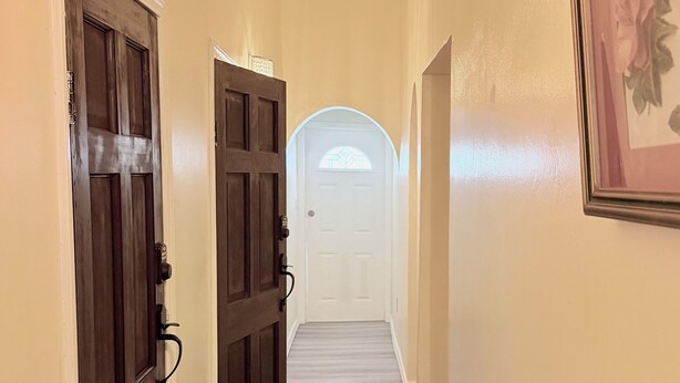 Un corridoio con porte in legno e una porta bianca in fondo.