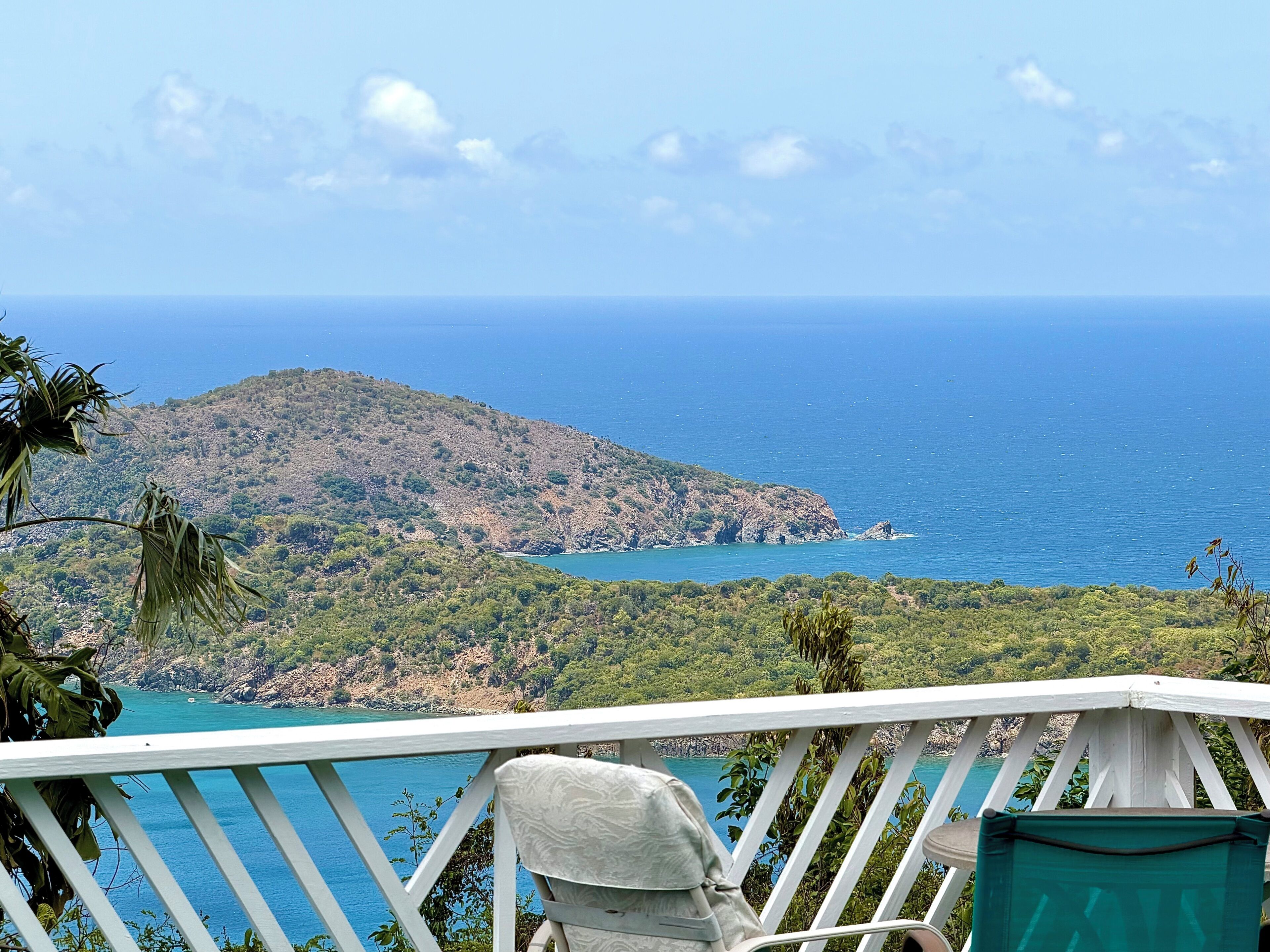 A balcony with a view of a mountainous coastline and the sea.