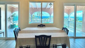 Un'area pranzo con un lampadario, ampie finestre e vista sull'esterno.