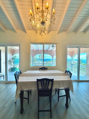 A dining area with a chandelier, large windows, and a view of the outdoors. - 3-bedroom estate in peaceful Charlotte Amalie East with AC (St. Thomas)