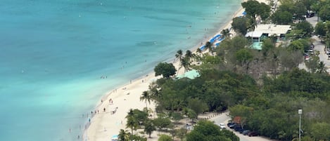 A coastal area with a beach, a road, and a building with a green roof.
