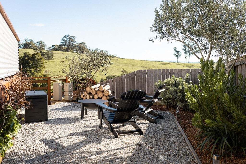 Eine Terrasse mit Gartenmöbeln, einem Holzzaun und einem Kiesweg.