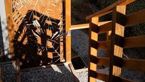 Eine Holztreppe führt zu einer Terrasse mit Gartenmöbeln und einem schmiedeeisernen Geländer.