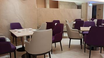 Un restaurante con varias mesas y sillas, paredes de mármol y un diseño moderno.