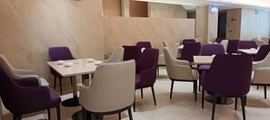 Ein Restaurant mit mehreren Tischen und Stühlen, Marmorwänden und modernem Design.