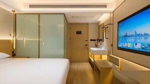 Habitación de hotel con cama, televisión, baño y vista panorámica de la ciudad.