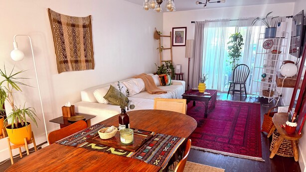 Ein modernes Wohnzimmer mit einem Holzes Esstisch, einem weißen Sofa und einem roten Teppich.
