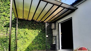 Un bâtiment moderne doté d’un patio couvert, d’une porte en métal et d’une entrée.