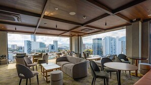 Un'accogliente hall d'hotel moderna con vista sulla città, sedute confortevoli e un'ampia vetrata.