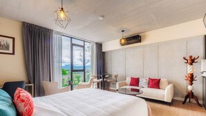 Camera d'albergo con un ampio letto, una poltrona, un tavolo da pranzo e vista sull'esterno.