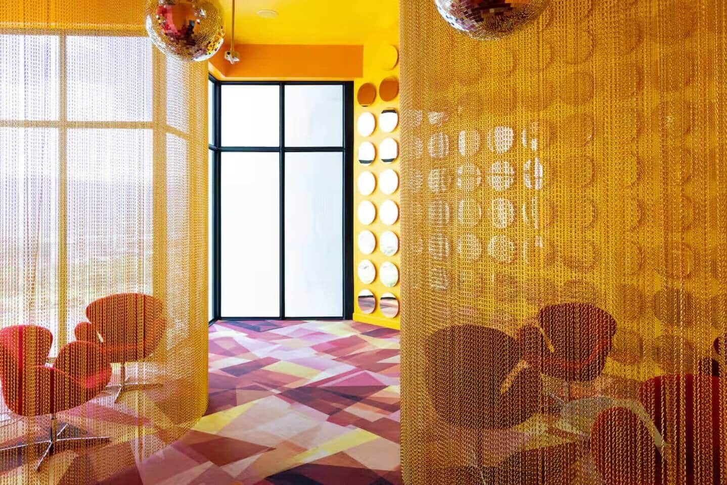 A room with a large window, a patterned floor, and a wall with circular decorations.