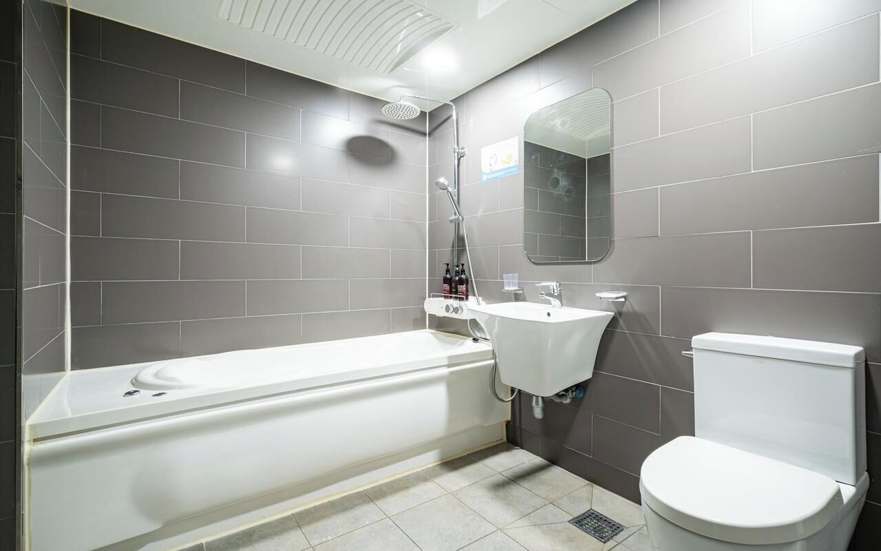 Un baño con bañera, lavamanos, inodoro y espejo.